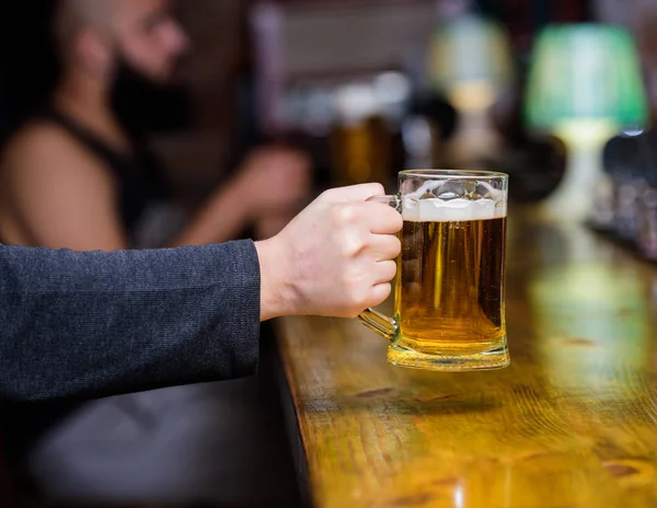 泡と新鮮なドラフト ビールとグラス。男性の手は冷たいおいしいビールでいっぱいのマグカップを保持バーで。金曜日レジャー伝統。ビールのパブの概念。バーのカウンターでビール ジョッキ デフォーカス背景 — ストック写真