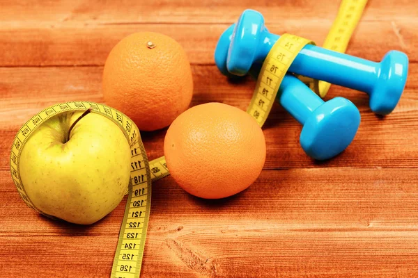 meter tape with dumbbells weight, apple, orange, diet concept