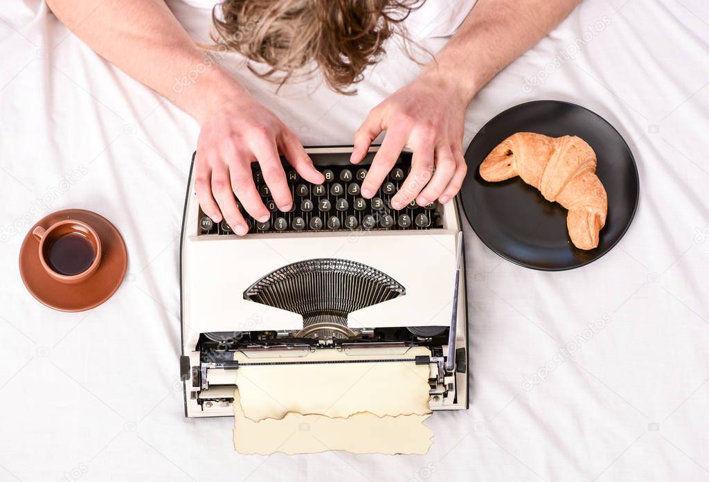 Old typewriter on bedclothes. Male hands type story or report using vintage typewriter equipment. Writing routine. No day without chapter. Vintage typewriter concept. Man typing retro writing machine