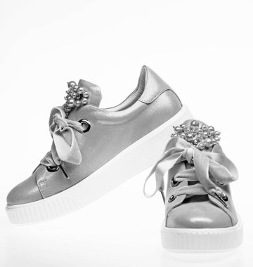 Son moda spor ayakkabı kavramı. Ayakkabı kız ve kadınlar için inci boncuklar ile dekore edilmiştir. Kadife kurdela ile soluk pembe kadın spor ayakkabı çifti. Şirin ayakkabılar beyaz arka plan üzerinde izole