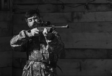 Sakallı kamuflaj elbiseler, ahşap iç arka plan giyer. Maço gamekeepers evinde sıkı yüzünde. Avcı, avcılık, kopya alanı daha önce silah nişan ile acımasız hipster. Avcı kavramı