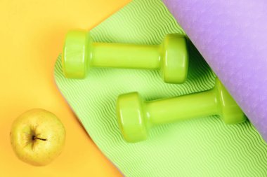 Dalgalı yeşil ve sarı arkaplanda plastik dambıllar