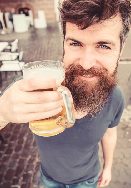 Ο τύπος έχει υπόλοιπο με κρύα μπύρα. Hipster στο χαμογελαστό πρόσωπο πίνοντας μπύρα εξωτερική. Έννοια βαρελίσια μπύρα. Ο άνθρωπος με το γυαλί κατέχει γένια και μουστάκι με μπύρα ενώ χαλαρώνετε στη βεράντα του καφέ — Φωτογραφία Αρχείου