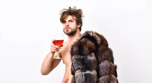 Health and wellbeing. Richness and luxury concept. Rich athlete enjoy his life. Guy attractive rich posing fur coat on naked body. Sexy sleepy rich macho tousled hair drink wine isolated on white