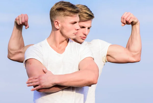 Men twins muscular brothers sky background. Men strong muscular athlete bodybuilder posing confidently in white shirts. Sport lifestyle and healthy body. Attractive twins. Handsome strong twins