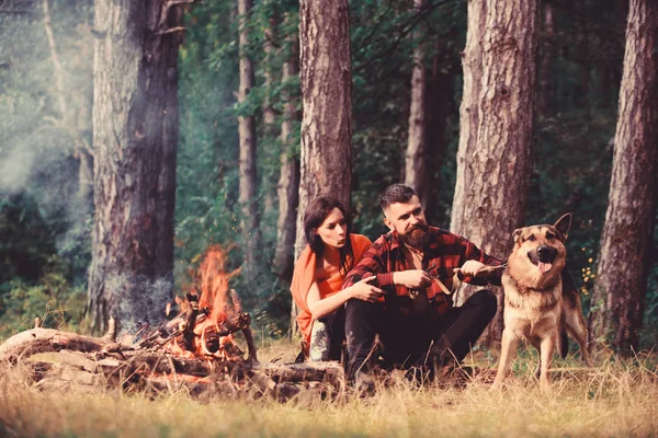 Couple with german shepherd dog near bonfire,