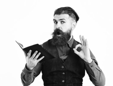 Sakallı adam elinde şaşkın suratıyla not defteri tutuyor.