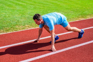 Yetişkin runner yarış Stadyumu'nda hazırlayın. Nasıl yayınlanmaya başlaması. Profesyonel atlet spor ipuçları. Adam atlet runner standı düşük başlangıç pozisyonu stadyum yolu. Zafer için çaba. Runner gitmeye hazır