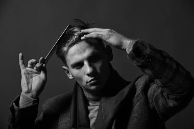 Stilist ciddi bir yüz ile saç modeli yapar. Vintage tarzı erkekte