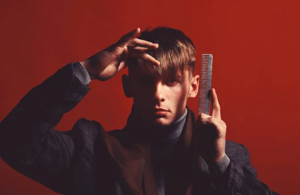 Barber in suit and scarf with comb on red background