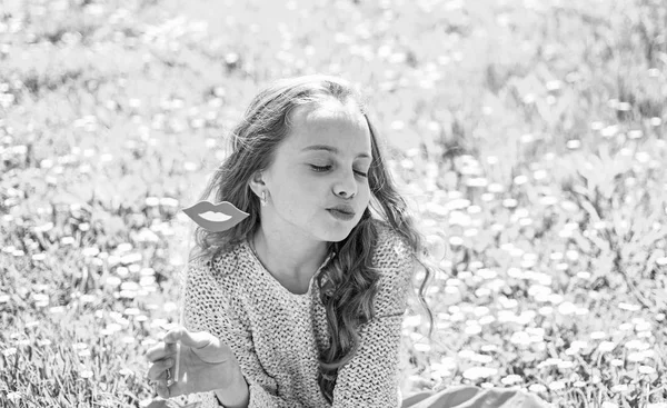 Kuss-Konzept. Mädchen auf küssendem Gesicht verbringen Freizeit im Freien. Kind posiert mit lächelndem Mund aus Pappe. Mädchen sitzt auf Gras auf Grasfläche, grüner Hintergrund — Stockfoto