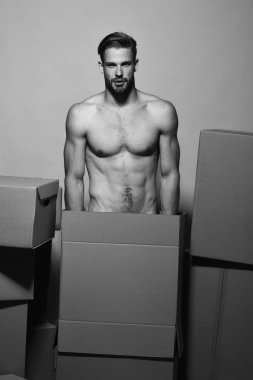Çıplak gövdeli adam kutuların arkasında duruyor.