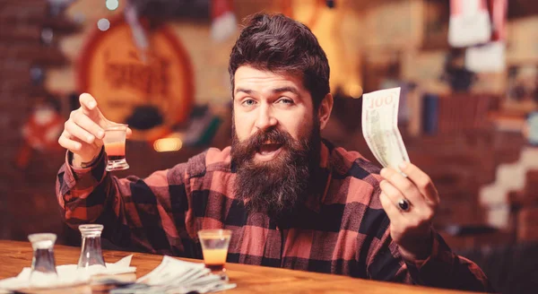 Hipster holds money, cash to buy more alcohol.
