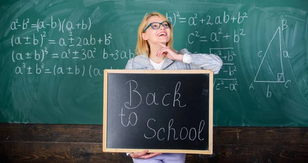 Professeur heureux d'accueillir les élèves. Commencez l'année scolaire. Meilleures façons d'accueillir les élèves à l'école. La maîtresse garde l'inscription au tableau noir à l'école. C'est l'heure de l'école agai — Photo