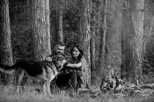 夫妇拍拍德国牧羊犬靠近篝火，自然背景. — 图库照片