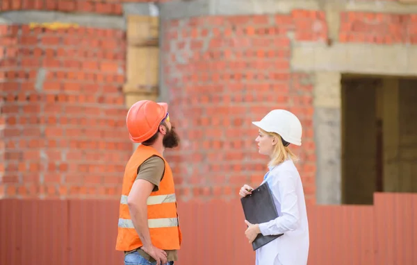 Discuta el proyecto de progreso. Concepto de industria de la construcción. Mujer ingeniera y constructora brutal barbuda discuten el progreso de la construcción. Gestión de proyectos de construcción. Proyecto industrial de construcción — Foto de Stock