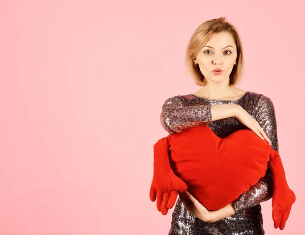 Dama con el pelo rubio pone sus brazos alrededor del corazón del juguete . —  Fotos de Stock