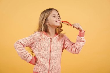 Şeker kız turuncu arka planda poz verir.