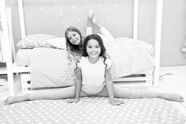 E 'ora dello stretching serale. Carino allenamento ginnasta diviso con un amico. Ragazza bambino seduto diviso in camera da letto. Amici ginnasti si sostengono a vicenda. Stile di vita regime sportivo. Ragazza bambino pigiama carino stretching — Foto Stock