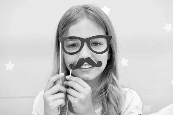 Girl pose with photo booth props glasses and mustick in bedroom. Κορίτσι με γυαλιά για πάρτι. Το παιδί μιμείται τον ανδρισμό ή θέλει να μοιάζει με τον πατέρα της. Παιδί με μουστάκι και γυαλιά — Φωτογραφία Αρχείου