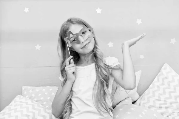 I am super star. Girl with long blonde curly hair posing photo booth props. Pajamas party concept. Girl star shaped eyeglasses at pajamas party. Cheerful young lady posing with eyeglasses