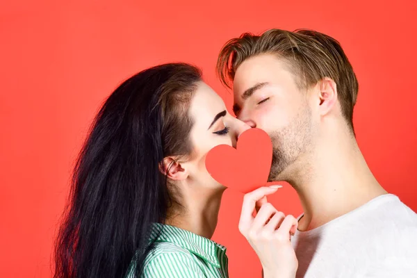 Romantic kiss concept. Couple in love kissing and hide lips behind heart card. Sensual kiss of lovely couple close up. Man and woman romantic kiss. Love and foreplay. Celebrate valentines day