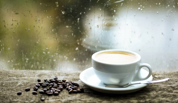 Podzimní zatažené počasí lepší nápoj na kofein. Káva se těší na deštivý den. Čerstvá uvařená káva bílý hrnek a fazole na okenní parapet. Mokré skleněné okno a šálek horké kávy. Káva Ranní rituál — Stock fotografie
