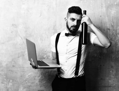 Çalışma sabah gece partiden sonra kavramı: adam sakallı ve bej renkli arka plan üzerinde üzgün yüz ifadesi tutan bir el ve onun yanında şarap şişe içinde laptop vardı