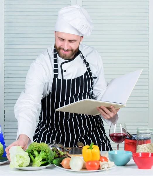 Måltidskunskap koncept. Man lära dig recept. Förbättra matlagning skicklighet. Boka familjerecept. Ultimata matlagning guide för nybörjare. Enligt receptet. Mannen skäggig kock Matlagning mat. Guy läsa bok recept — Stockfoto