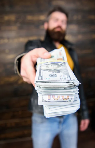 Man give cash money bribe. Richness and wellbeing. Mafia business. Man brutal bearded hipster wear leather jacket and hold cash money. Illegal profit and black cash. Guy mafia dealer with cash profit