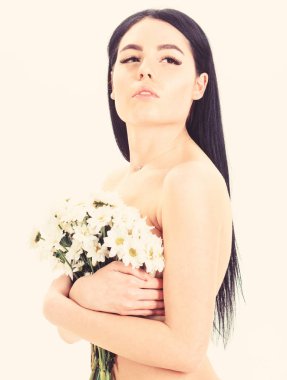 Bayan göğüsler üzerinde beyaz izole çiçekli kapsar. Sağlıklı ciltle pürüzsüz kadınla çekici görünüyor. Cilt sağlığı kavramı. Sakin yüz kız çıplak durumda ve papatya çiçeği göğüs önünde tutar