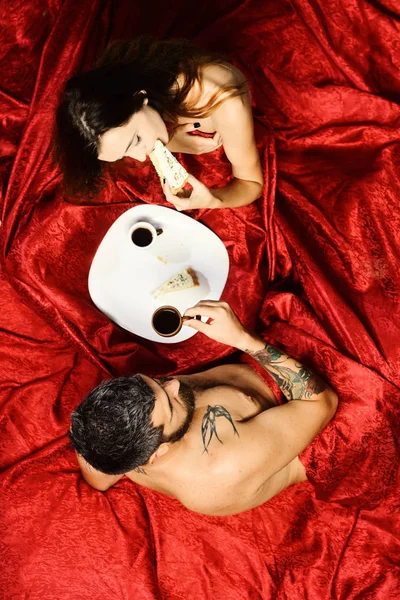 Birbirine aşık çiftler kırmızı çarşaflarda yatar. Sakallı adam — Stok fotoğraf