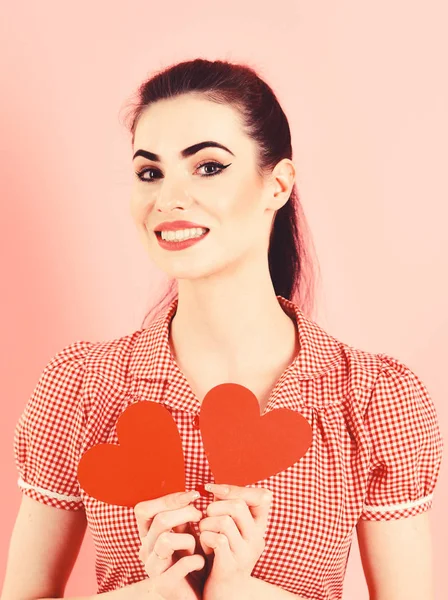 Mujer sonriente bastante feliz en vestido rosa sosteniendo corazones rojos sobre fondo rosa — Foto de Stock