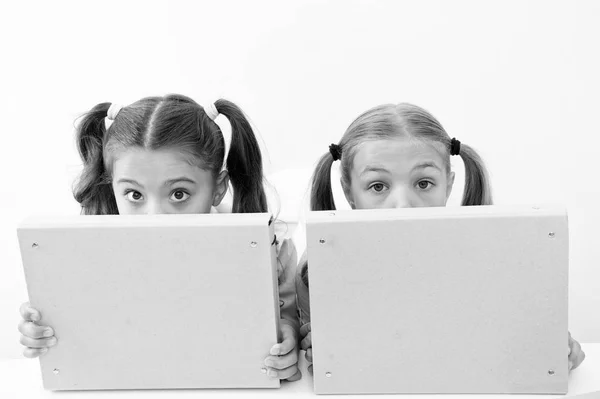 Kleine unbeholfene Mädchen verstecken Gesichter hinter Aktenordnern. Kleine unbeholfene Mädchen genießen das gemeinsame Spielen — Stockfoto