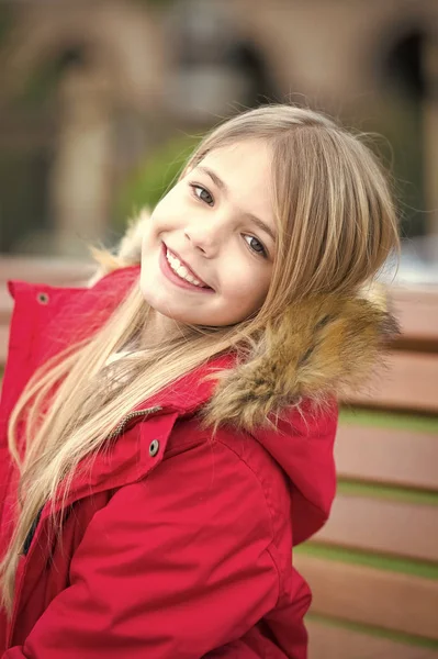 Meisje in de rode jas zitten op bankje in park — Stockfoto