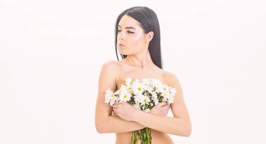 Sakin yüz kız çıplak durumda ve papatya çiçeği göğüs önünde tutar. Bayan göğüsler üzerinde beyaz izole çiçekli kapsar. Sağlıklı ciltle pürüzsüz kadınla çekici görünüyor. Cilt sağlığı kavramı