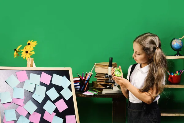 Menina detém despertador verde perto de notas pegajosas no quadro negro — Fotografia de Stock