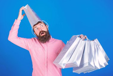 Adam deli göz ve açık ağız gümüş kağıt torba kafasına takıyor. Konsept alışveriş Alışverişkoliğin mevsimlik satış hakkında çıldırıyor. Üzerinde mavi arka plan izole pembe gömlekli sakallı adam