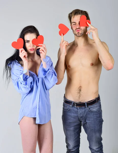 Sexual relations between people. Man sexy torso and woman in his shirt hold red hearts valentines cards. Love and relations concept. Romantic relations. Couple in love happy with their relations — Stock Photo, Image