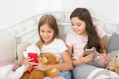 Büyük resimleri paylaşma. Mutlu Noeller ve mutlu yeni yıl tebrik. Küçük kızlar yatakta smartphone kullanın. Cep telefonu ile mutlu küçük çocuklar. Noel ve yeni yıl hediyesi telefonla sipariş