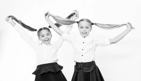 Las niñas muestran colas largas. Niños de escuela. Los niños felices disfrutan de un cabello saludable. La peluquería es nuestra pasión — Foto de Stock