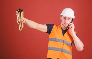 Adam inşaat telefon, kırmızı zemin üzerine denetlemektedir. Mühendis, mimar meşgul yüzündeki telefonla konuşuyor, planları tutan, parmakla işaret ederek, alan Kopyala. Tedarik malzemeleri kavram oluşturma