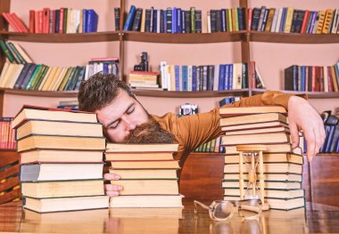 Overstudied kavramı. Öğretmen ya da öğrenci sakallı defocused kitaplar üzerinde uykuya. Yüz uyuyan adamın kitap yığınları arasında yatıyordu, kitaplığında, arka plan üzerinde kitap rafı öğrenimleri sırasında uykuya