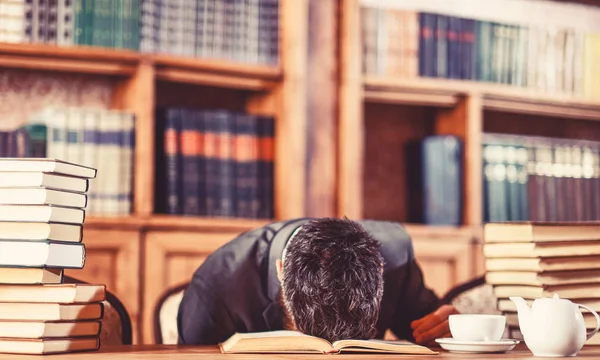 Guy is overworked and sleeps on table.