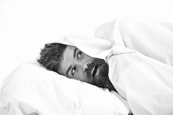 Человек с бородой и усами прячется в постели под одеялом — стоковое фото