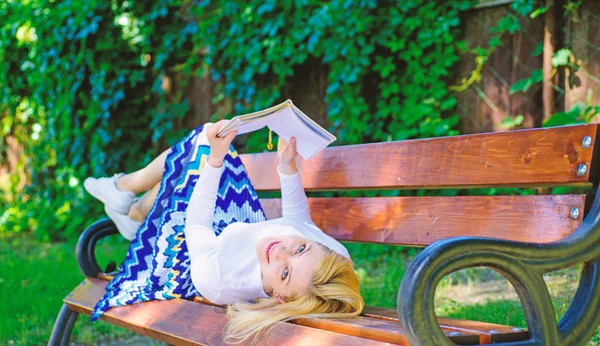 Interesting book. Smart and pretty. Smart lady relaxing. Girl reading outdoors while relaxing on bench. Girl lay bench park relaxing with book, green nature background. Woman spend leisure with book