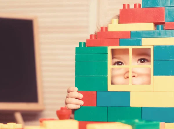 Kid looking through window of toy house made of blocks. — Stock Photo, Image