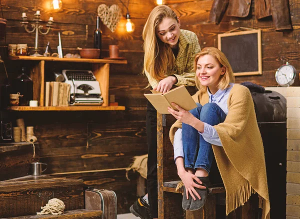 Chicas rubias con sonrisas brillantes leyendo juntas. Mujer envuelta en una manta de lana sosteniendo el libro. Madre e hija charlando y divirtiéndose. Mamá enseñando literatura infantil adolescente, concepto de educación en el hogar —  Fotos de Stock