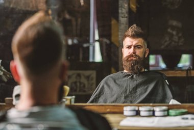 Siyah pelerin ile kaplı sakallı adam ayna önünde salonların sandalyede oturur. Saç kesimi sonucu kontrol sakallı hippi. Berber kavramı. Hipster berber sakal müşterilerinden olan adam