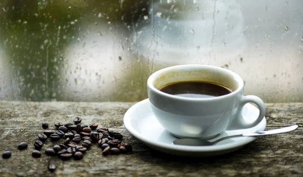 Automne temps nuageux mieux avec de la caféine boisson. Profiter du café le jour de pluie. Rituel matin café. Café frais infusé tasse blanche et haricots sur le rebord de la fenêtre. fenêtre en verre humide et tasse de café chaud — Photo